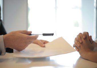 Close-up of a contract signing with hands over documents. Professional business interaction.