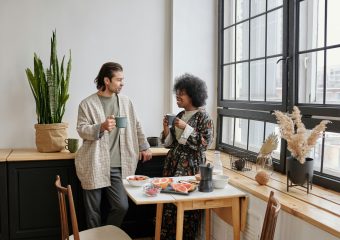 A joyful couple enjoys a morning coffee and healthy breakfast of grapefruit in their cozy apartment.